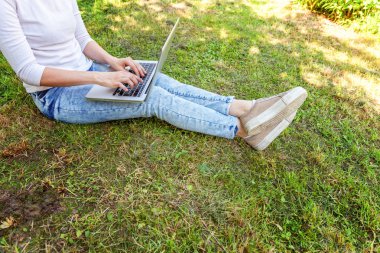 Kadın ayakları üzerinde yeşil çim şehir Park, dizüstü pc bilgisayar üzerinde çalışan eller çimen. Serbest iş kavramı