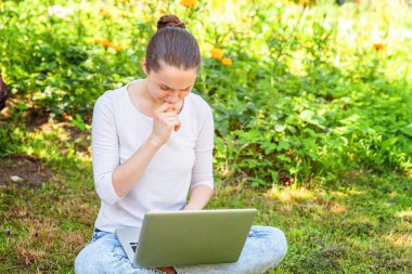 Dizüstü pc bilgisayar üzerinde çalışan Şehir Parkı yeşil çim Çimenlikte oturan genç kadın. Serbest iş kavramı