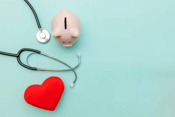 Medicine doctor equipment stethoscope or phonendoscope piggy bank and red heart isolated on trendy pastel blue background — Stock Photo, Image