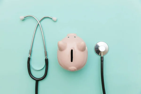 Geneeskunde arts apparatuur stethoscoop of phonendoscoop en Piggy Bank geïsoleerd op trendy pastel blauwe achtergrond — Stockfoto