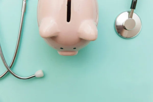 Equipamento médico medicina estetoscópio ou fonendoscópio e porquinho banco isolado no moderno fundo azul pastel — Fotografia de Stock