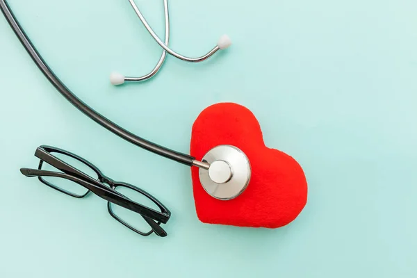 Equipamento de medicina estetoscópio ou óculos de fonendoscópio e coração vermelho isolado no moderno fundo azul pastel. Dispositivo de instrumento para médico. Conceito de seguro de vida em saúde — Fotografia de Stock