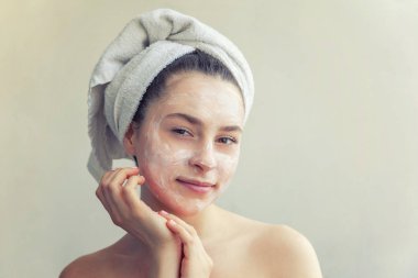 Yüzünde beyaz besleyici maske veya krem ile havlu kadın güzellik portresi, beyaz arka plan izole