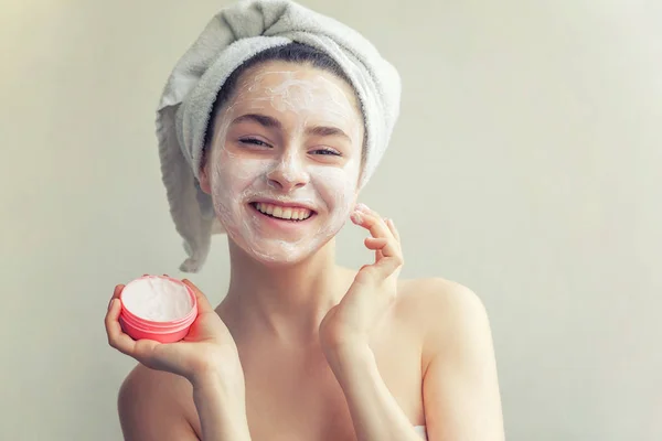 Yüzünde beyaz besleyici maske veya krem ile havlu kadın güzellik portresi, beyaz arka plan izole