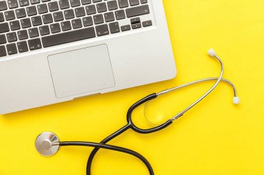 Stetoskop klavye dizüstü bilgisayar sarı arka plan üzerinde izole. Modern tıbbi Bilgi teknolojisi ve sofware gelişmeler kavramı. Bilgisayar ve gadget tanılama ve onarım