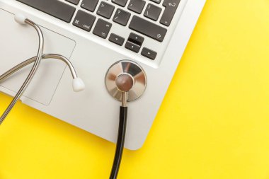 Stetoskop klavye dizüstü bilgisayar sarı arka plan üzerinde izole. Modern tıbbi Bilgi teknolojisi ve sofware gelişmeler kavramı. Bilgisayar ve gadget tanılama ve onarım