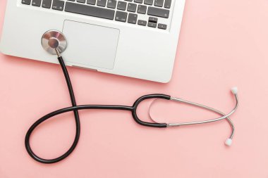 Pembe arka plan üzerinde izole Stetoskop klavye dizüstü bilgisayar. Modern tıbbi Bilgi teknolojisi ve sofware gelişmeler kavramı. Bilgisayar ve gadget tanılama ve onarım
