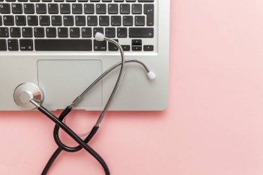 Pembe arka plan üzerinde izole Stetoskop klavye dizüstü bilgisayar. Modern tıbbi Bilgi teknolojisi ve sofware gelişmeler kavramı. Bilgisayar ve gadget tanılama ve onarım