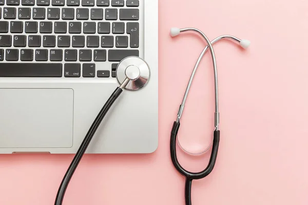 Stethoscope keyboard laptop computer isolated on pink background. Modern medical Information technology and sofware advances concept. Computer and gadget diagnostics and repair