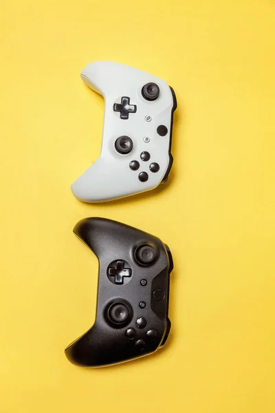 Bianco e nero due joystick su sfondo giallo. Concorso di gioco per computer concetto di confronto di controllo videogame — Foto Stock