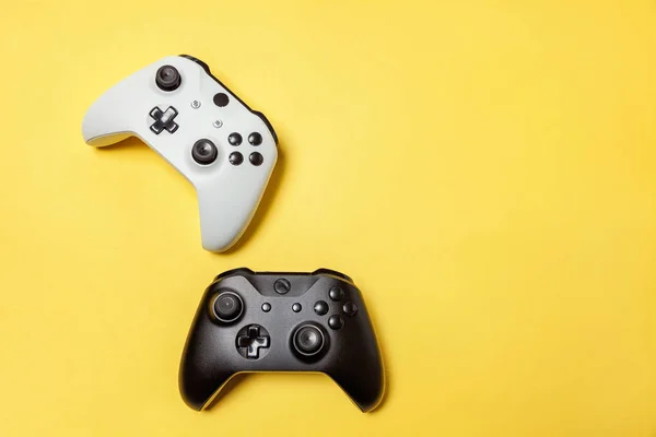 Branco e preto dois joystick no fundo amarelo. Concorrência de jogos de computador conceito de confronto de controle de videogame — Fotografia de Stock