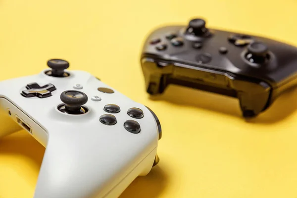 Fehér és fekete két joystick sárga háttéren. Számítógépes játék verseny videogame kontroll konfrontáció koncepció — Stock Fotó