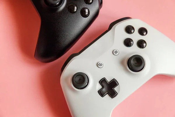 Branco e preto dois joystick no fundo rosa. Concorrência de jogos de computador conceito de confronto de controle de videogame — Fotografia de Stock