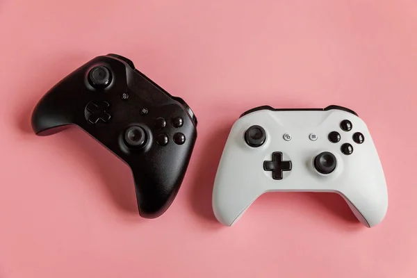 Branco e preto dois joystick no fundo rosa. Concorrência de jogos de computador conceito de confronto de controle de videogame — Fotografia de Stock