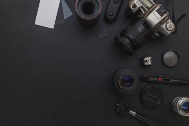 DSLR kamera sistemi, kamera Temizleme Kiti, koyu siyah masa arka planda objektif ve kamera aksesuarı ile fotoğrafçı çalışma alanı
