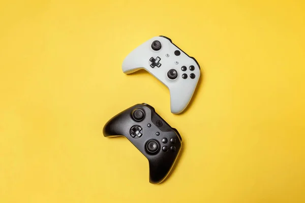 Blanco y negro dos joystick sobre fondo amarillo. Juego de ordenador competencia videojuego control confrontación concepto —  Fotos de Stock