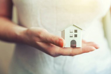 Minyatür beyaz oyuncak ev tutan eller kadın kadın