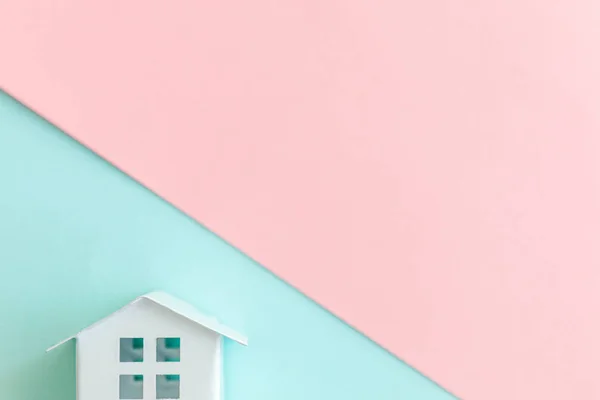 Miniaturowe zabawki biały dom na tle pastel niebieski i różowy — Zdjęcie stockowe