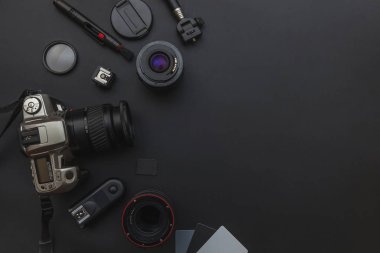 DSLR kamera sistemi, kamera Temizleme Kiti, koyu siyah masa arka planda objektif ve kamera aksesuarı ile fotoğrafçı çalışma alanı