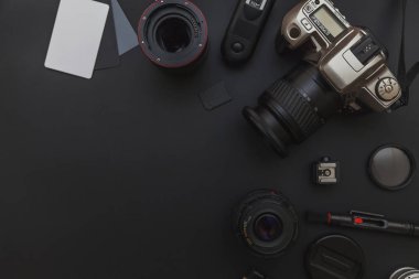 DSLR kamera sistemi, kamera Temizleme Kiti, koyu siyah masa arka planda objektif ve kamera aksesuarı ile fotoğrafçı çalışma alanı