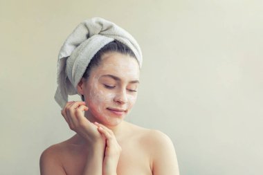 Yüzünde beyaz besleyici maske veya krem ile havlu kadın güzellik portresi, beyaz arka plan izole