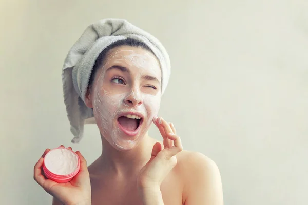 Retrato de belleza de mujer en toalla en la cabeza con máscara blanca nutritiva o crema en la cara, fondo blanco aislado —  Fotos de Stock