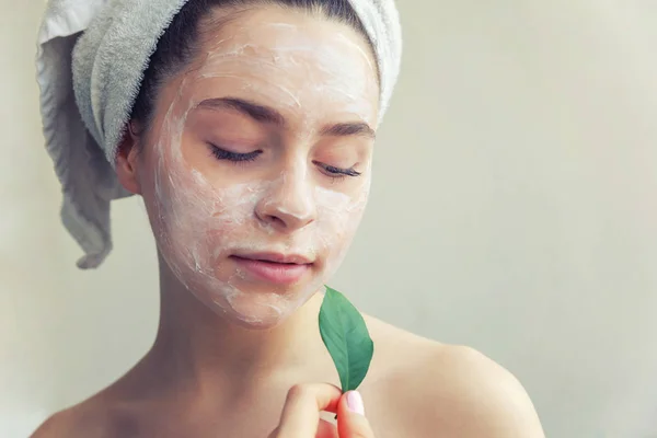 Vrouw gezicht met groen blad en crème of voedende masker — Stockfoto