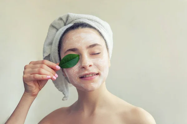 Vrouw gezicht met groen blad en crème of voedende masker — Stockfoto