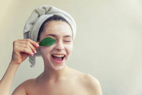 Vrouw gezicht met groen blad en crème of voedende masker — Stockfoto