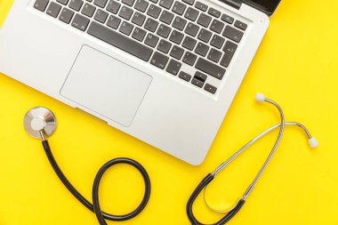 Stetoskop klavye dizüstü bilgisayar sarı arka plan üzerinde izole. Modern tıbbi Bilgi teknolojisi ve sofware gelişmeler kavramı. Bilgisayar ve gadget tanılama ve onarım
