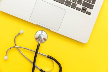 Stetoskop klavye dizüstü bilgisayar sarı arka plan üzerinde izole. Modern tıbbi Bilgi teknolojisi ve sofware gelişmeler kavramı. Bilgisayar ve gadget tanılama ve onarım