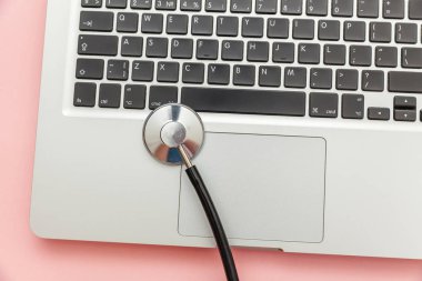 Pembe arka plan üzerinde izole Stetoskop klavye dizüstü bilgisayar. Modern tıbbi Bilgi teknolojisi ve sofware gelişmeler kavramı. Bilgisayar ve gadget tanılama ve onarım