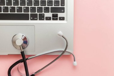 Pembe arka plan üzerinde izole Stetoskop klavye dizüstü bilgisayar. Modern tıbbi Bilgi teknolojisi ve sofware gelişmeler kavramı. Bilgisayar ve gadget tanılama ve onarım