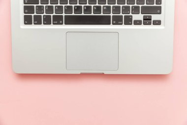 Pembe pastel masa arka planda izole klavye dizüstü bilgisayar. Modern bilgi teknolojisi ve yazılım gelişmeleri