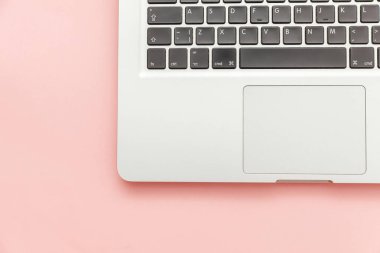 Pembe pastel masa arka planda izole klavye dizüstü bilgisayar. Modern bilgi teknolojisi ve yazılım gelişmeleri