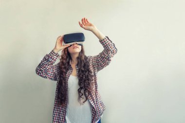 Beyaz arka planda sanal gerçeklik Vr gözlük kask kulaklık kullanarak giyen smile genç kadın. Sanal gerçeklik gözlüğü ile akıllı telefon kullanımı