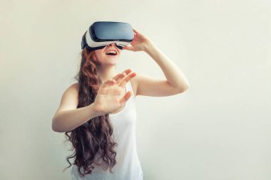 Beyaz arka planda sanal gerçeklik Vr gözlük kask kulaklık kullanarak giyen smile genç kadın. Sanal gerçeklik gözlüğü ile akıllı telefon kullanımı