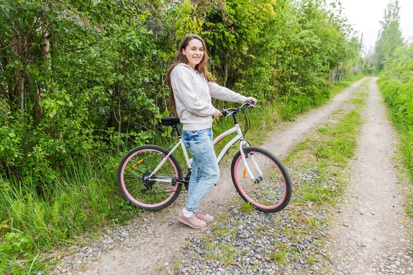 Young woman riding bicycle in summer city park outdoors. Active people. Hipster girl relax and rider bike