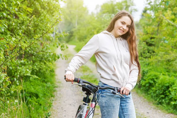 Young woman riding bicycle in summer city park outdoors. Active people. Hipster girl relax and rider bike