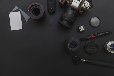 DSLR kamera sistemi, kamera Temizleme Kiti, koyu siyah masa arka planda objektif ve kamera aksesuarı ile fotoğrafçı çalışma alanı