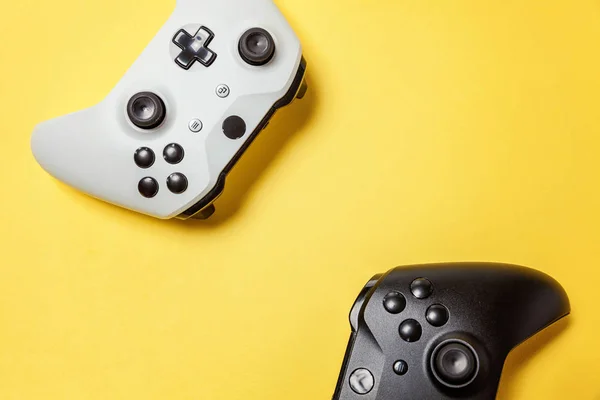 Branco e preto dois joystick no fundo amarelo. Concorrência de jogos de computador conceito de confronto de controle de videogame — Fotografia de Stock