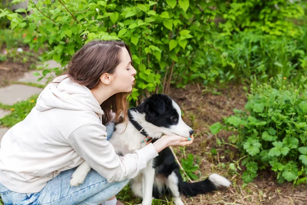 Glimlachend jong aantrekkelijk vrouw omarmen huging cute puppy hond Border Collie in zomer stadspark buiten achtergrond — Stockfoto