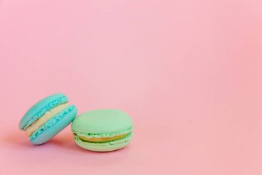 Pembe bir arka plan üzerinde mavi ve yeşil macaron