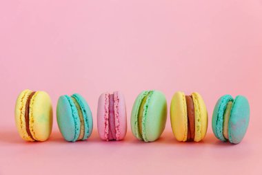Fransız tatlı kurabiye. Çok az yiyecek ekmek kavramı. Pembe mavi sarı yeşil macaron pembe bir arka plan üzerinde