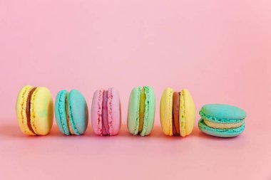 Fransız tatlı kurabiye. Çok az yiyecek ekmek kavramı. Pembe mavi sarı yeşil macaron pembe bir arka plan üzerinde