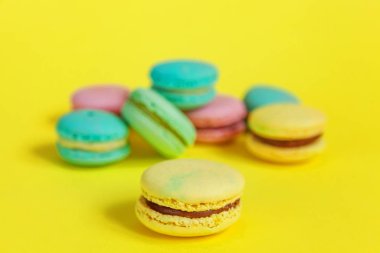 Fransız tatlı kurabiye. Çok az yiyecek ekmek kavramı. Pembe mavi sarı yeşil macaron Sarı zemin üzerine