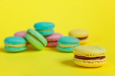 Fransız tatlı kurabiye. Çok az yiyecek ekmek kavramı. Pembe mavi sarı yeşil macaron Sarı zemin üzerine