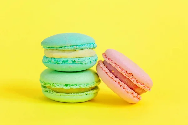 Galleta dulce francesa. Concepto mínimo de panadería de alimentos. Macaron azul y rosa sobre fondo amarillo — Foto de Stock