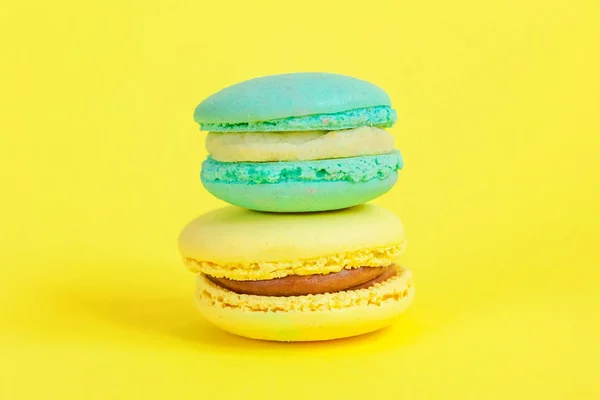 Galleta dulce francesa. Concepto mínimo de panadería de alimentos. Macaron azul y amarillo sobre fondo amarillo — Foto de Stock