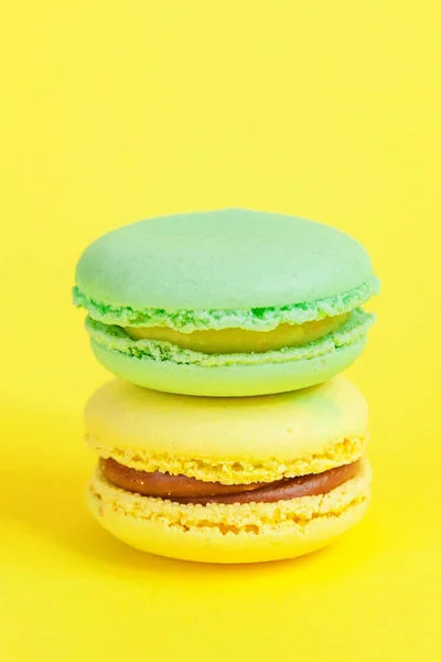French sweet cookie. Minimal food bakery concept. Blue and yellow macaron on yellow background